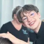 Jeune étudiant en coiffure souriant et dynamique en TP